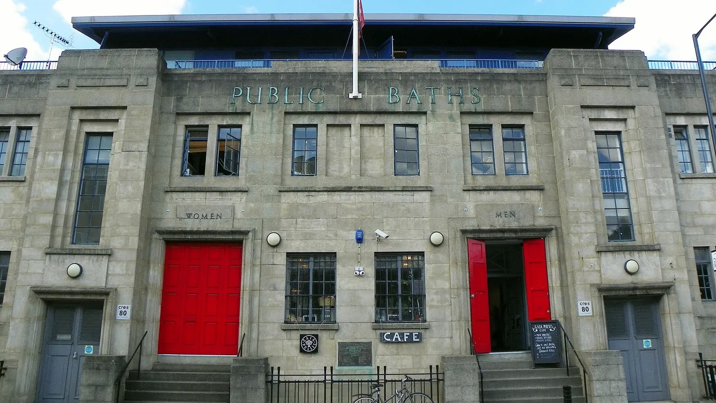 Art deco facade of the old public baths on Eastway, Hackney Wick, with red doors marked Women and Men