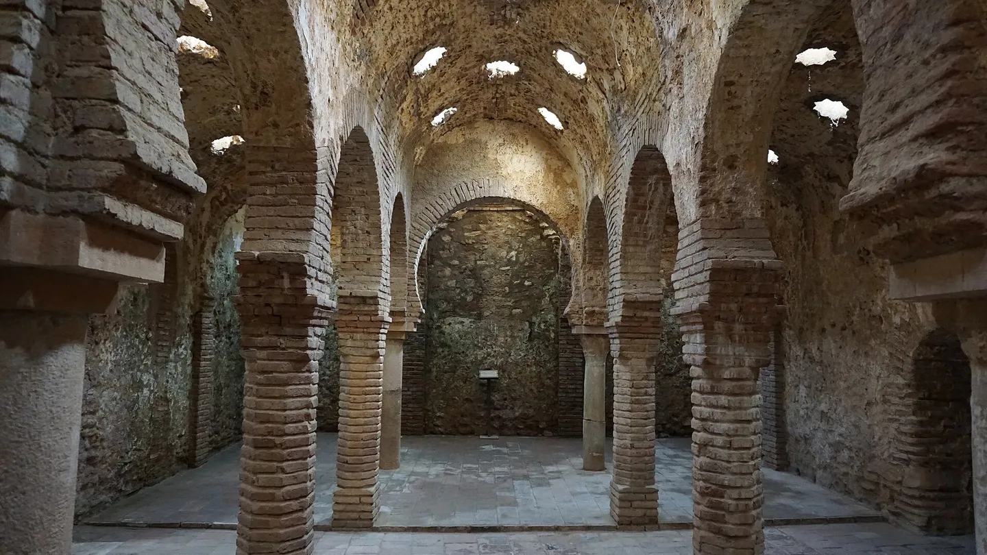 Central hall of the Arab baths in Ronda, with horseshoe arches on brick columns and star-shaped skylights in the vault