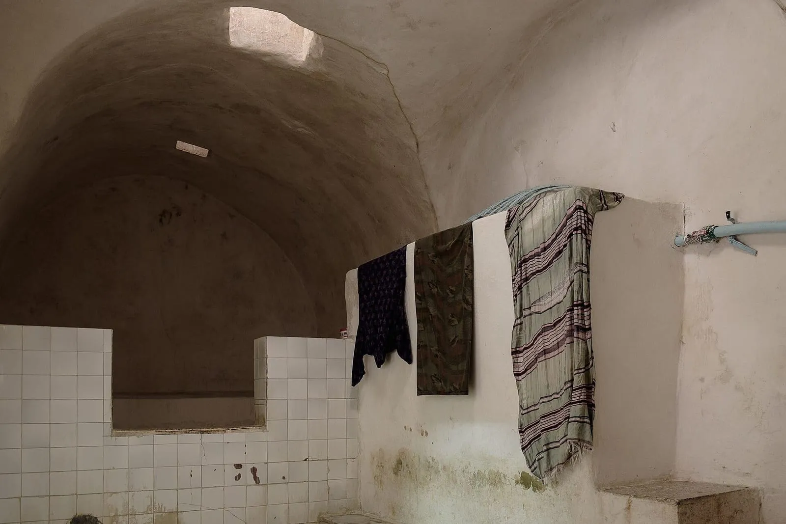 Caldarium of the Zeitouni hammam in Tunis, with white walls, vaulted niches and a stone basin