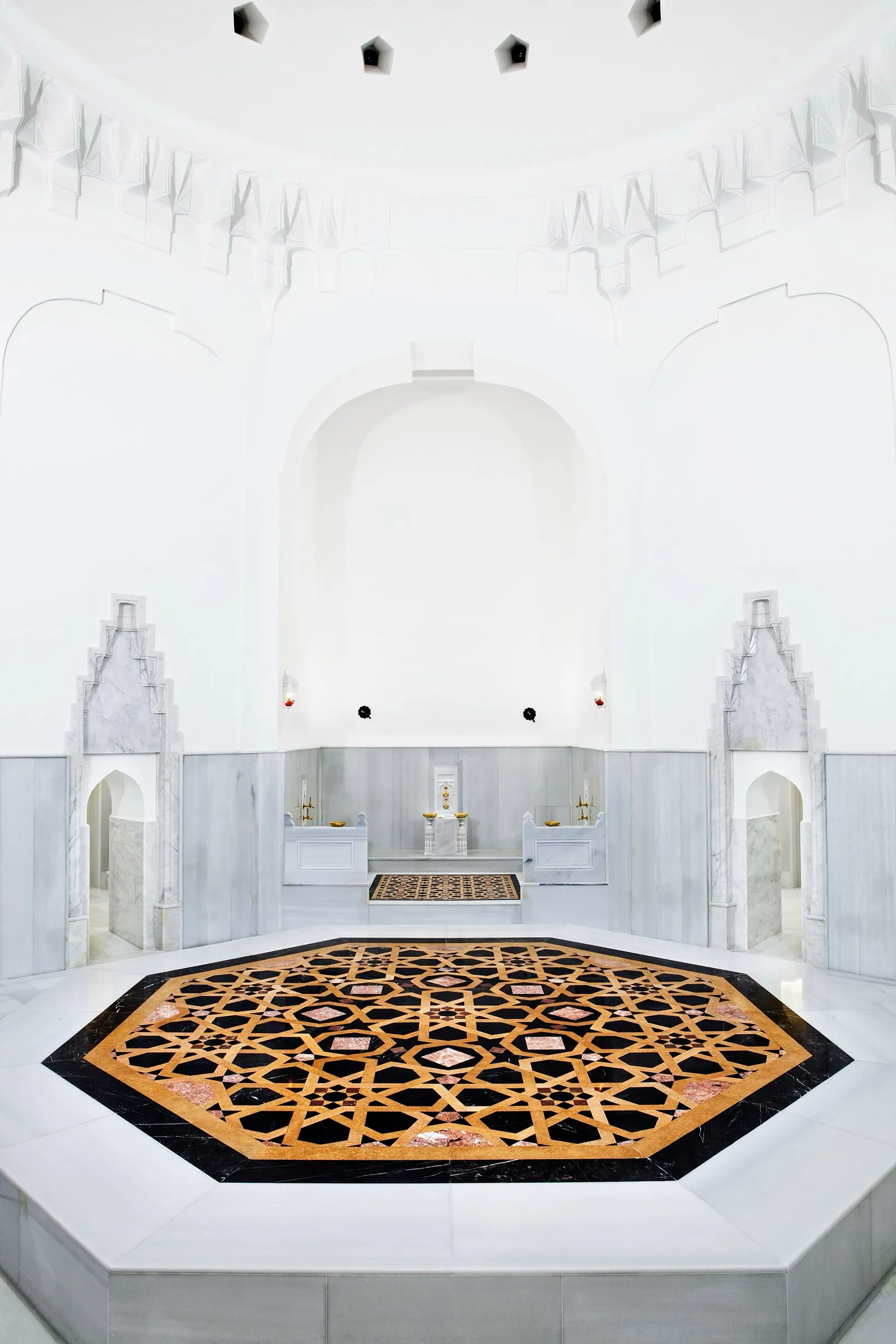 Hot room of the Hürrem Sultan Hamamı in Istanbul, with white marble walls, washing niches and an inlaid octagonal marble platform at the center