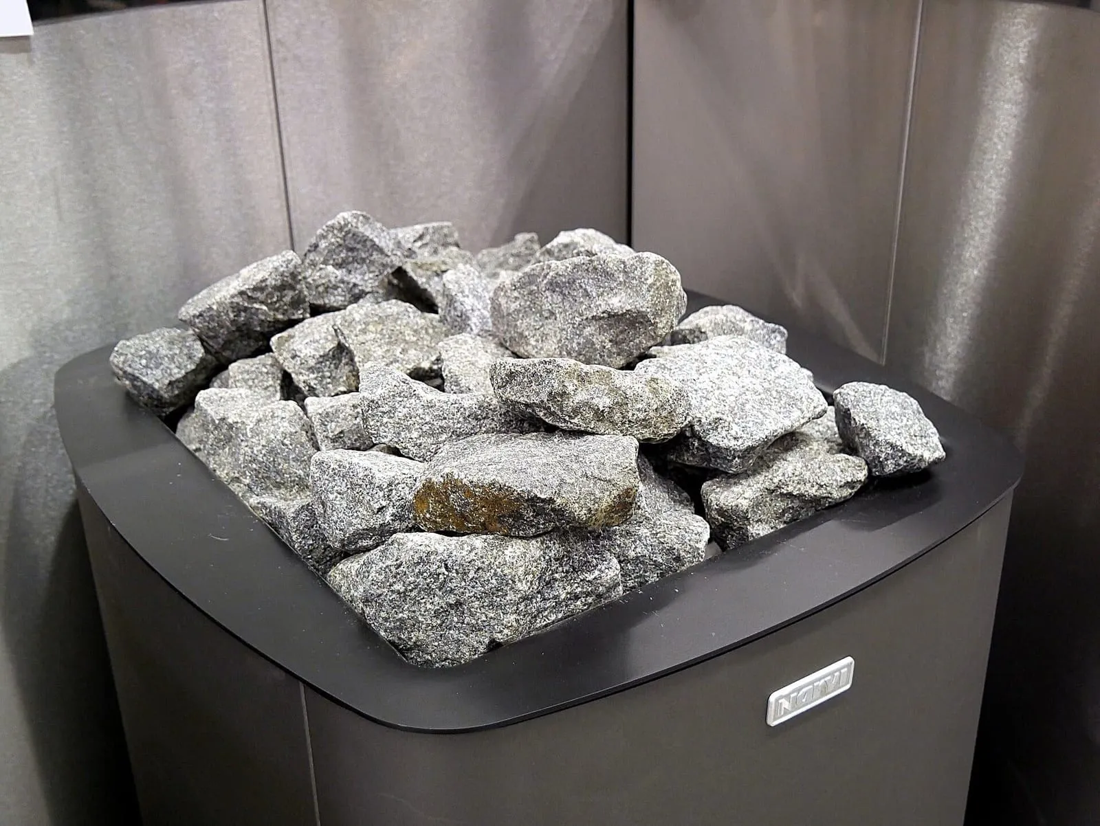 Gray stones stacked on top of a steel electric sauna heater