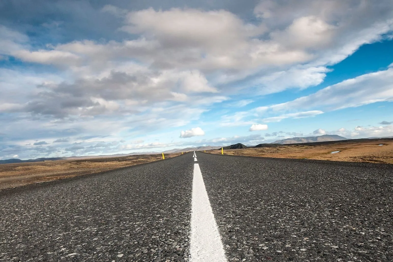 Iceland’s Ring Road, a straight asphalt road cutting through a lava field under clouds