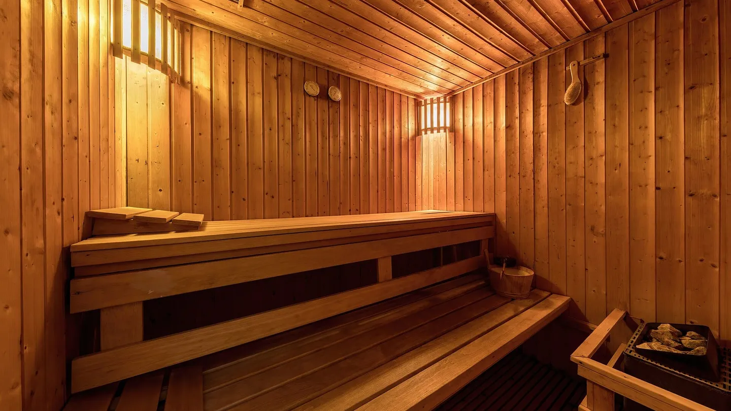 Interior of a sauna lined in pale wood, with two levels of benches and warm light, in Luang Prabang, Laos