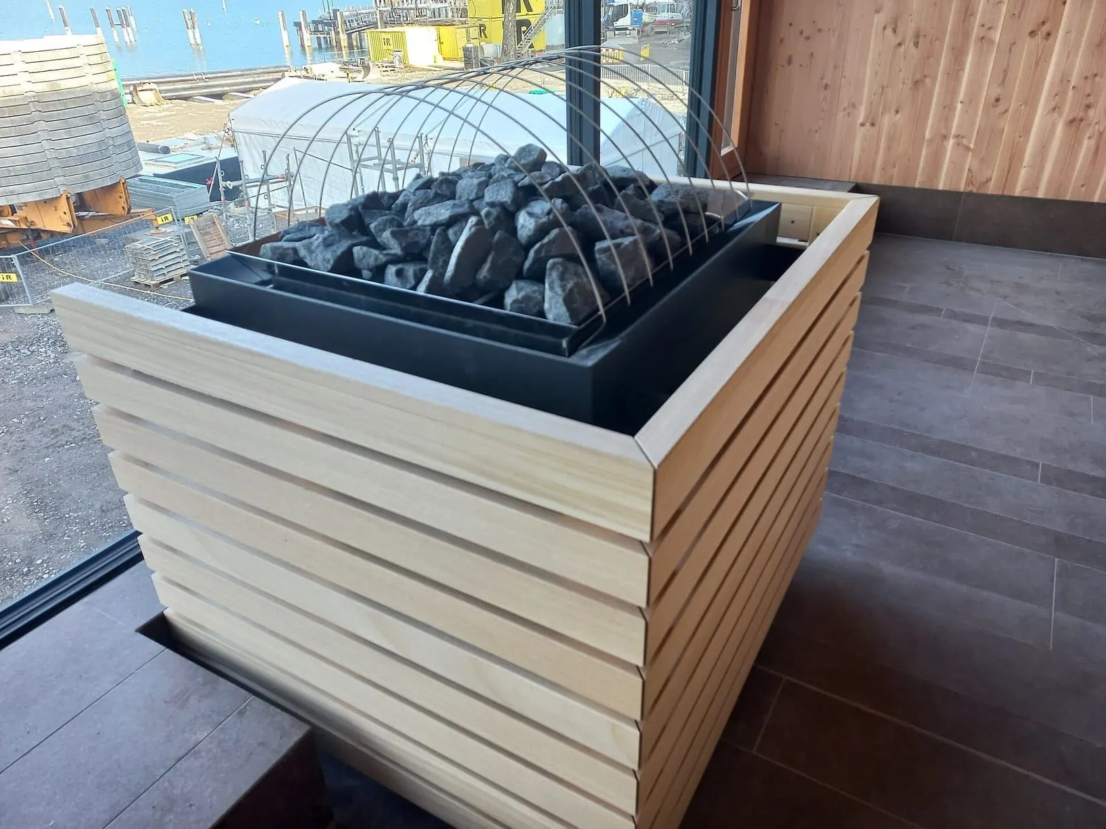 Sauna heater with stones, wrapped in timber slats, in a sauna still under construction in Bregenz