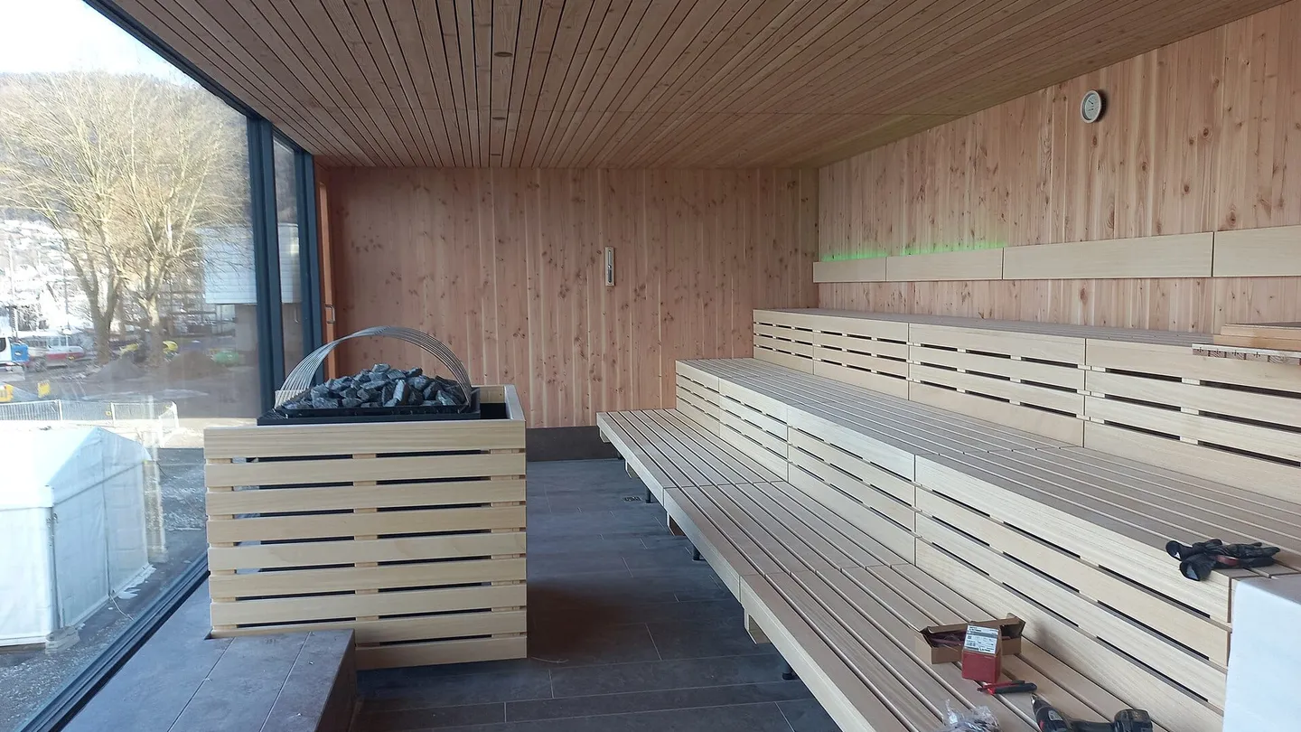 Sauna under construction at the Seebad in Bregenz, Austria, with pale timber benches, a heater and a window onto the lake