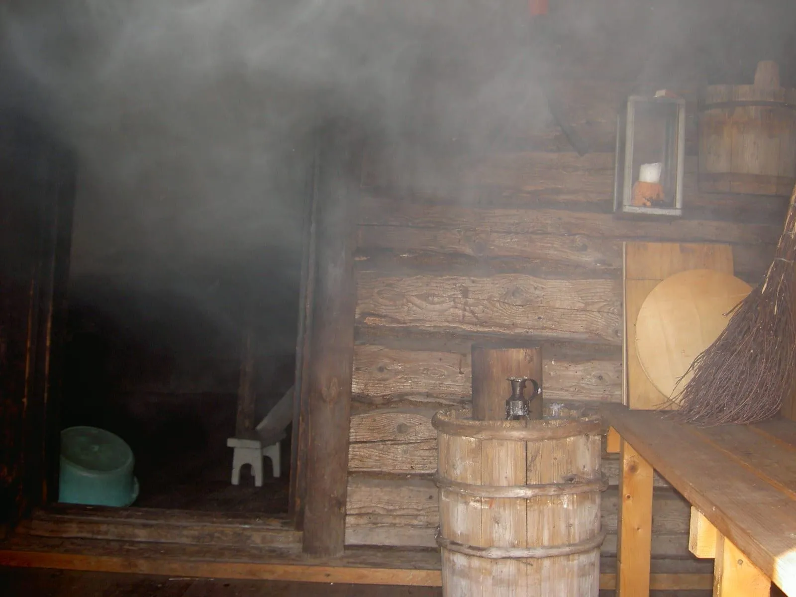 Interior of a Finnish smoke sauna in Uusikaupunki, with steam in the air, wooden benches and a bucket