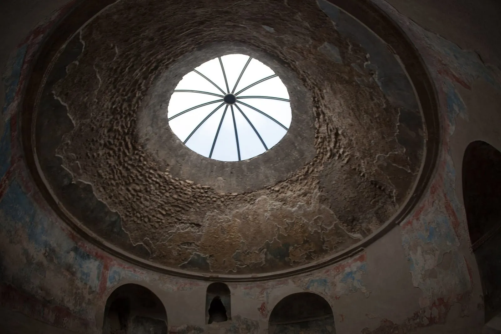 Domed room of the Stabian Baths in Pompeii, with an oculus in the ceiling, wall niches and remains of painted stucco